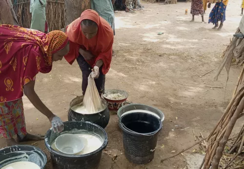 Moeders in crisisgebieden: twee vrouwen wassen kleren in emmers